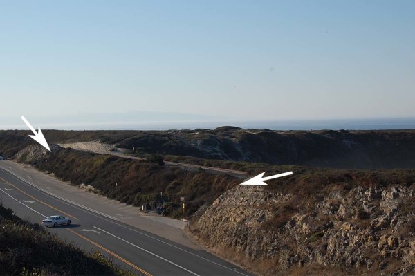 The inland view of the earthen berm on which the railroad tracks sit. The two arrows show the limits of the native bedrock, i.e., the Santa Cruz Mudstone.              In between the arrows is all fill for the embankment.