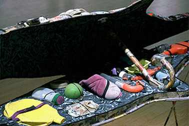 The interior contains larger objects found in streams and rivers. These are secured with snaps and bindings, then presented home-shopping-network-style during the performance. Image: Kim Abeles