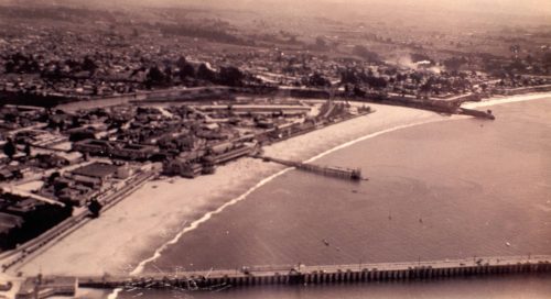 Aerial photo of Santa Cruz in 1930. You can see the Santa Cruz Municipal Wharf (foreground) and the Pleasure Pier (center). Photo: Gordon Woody, from the collection of Gerald Weber